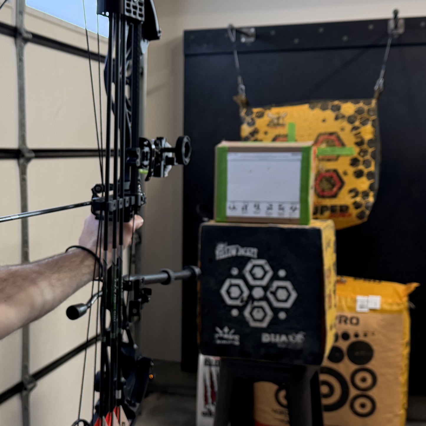 Person holding a bow with a Revelation Archery Printable Paper Tuning System and target in the background